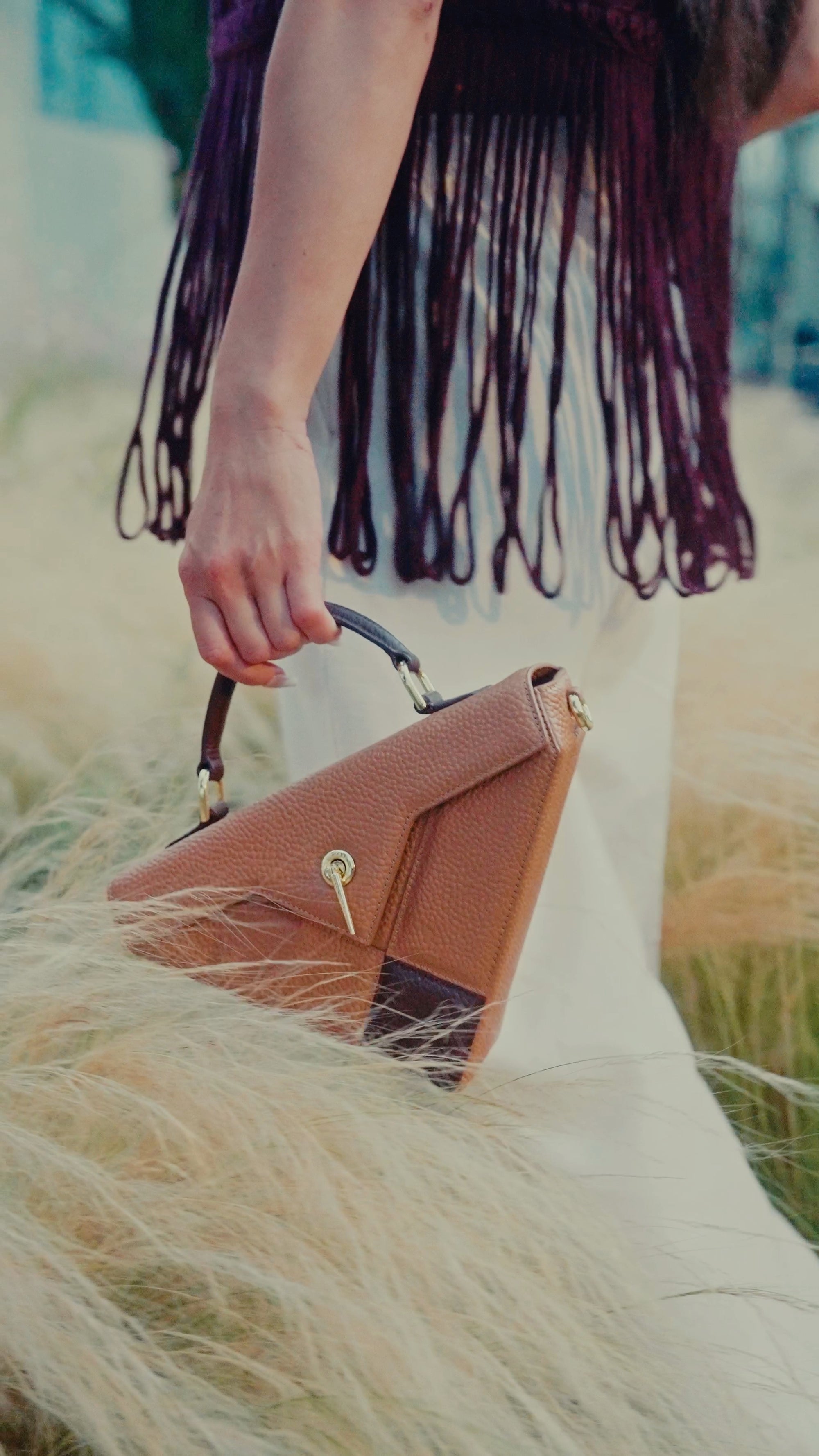 ARAS IDAAS Delta handbag, Roasted brown & Nomad camel, Italian vegetable-tanned leather hold by a model in the middle of Nature